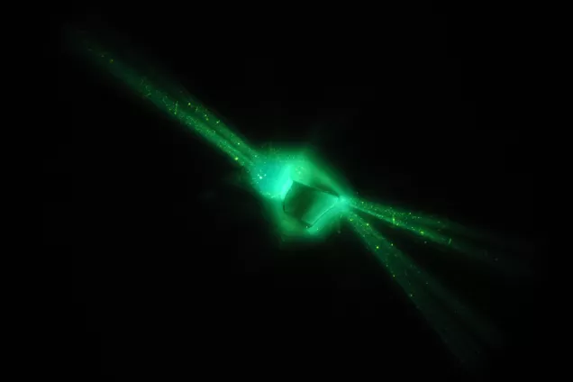 A photo showing green luminescent crystal and laser. 