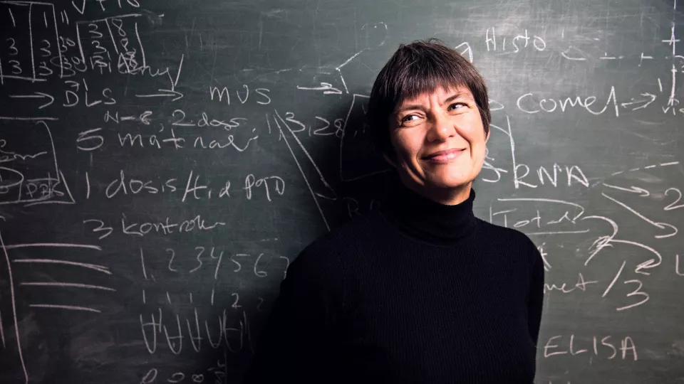 Photo of a woman in front of a black board.