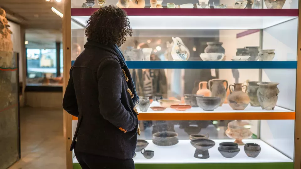 A woman is looking at shelves with clay objects.