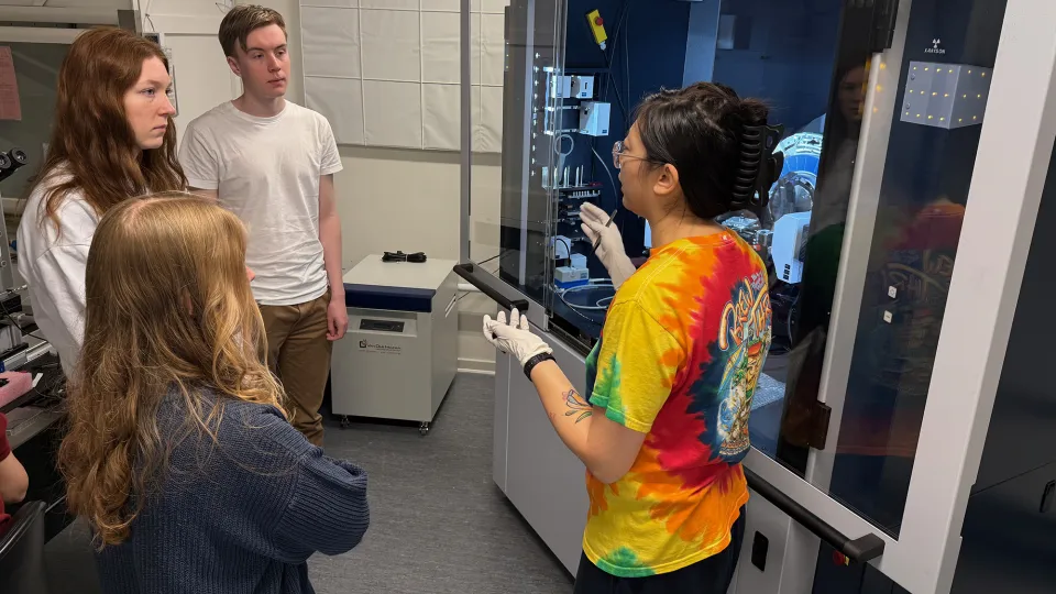 Four people in front of a Bruker XRD machine.