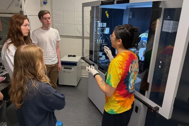Four people in front of a Bruker XRD machine.