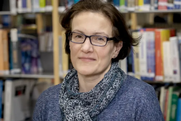 Photo of a woman in front of bookshelfs.