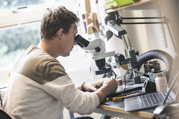 Photo of a man working a microscope.