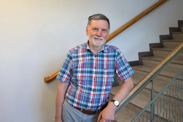Photo of a man standing in front of stairs.