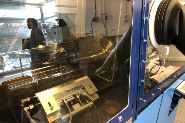 Photo of glass reflecting a person in lab clothing.