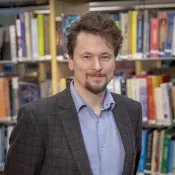 Photo of a man in front of a book shelf.
