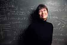 Photo of a woman in front of a black board.