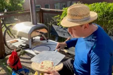 Man in straw hat puts pizza in table top oven