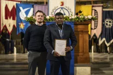 Photo of two men at a graduation ceremony.
