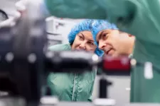 Photo of a woman and a man in protective lab clothing.