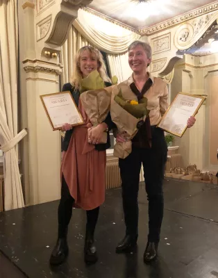 Photo of two people with diplomas and flowers.