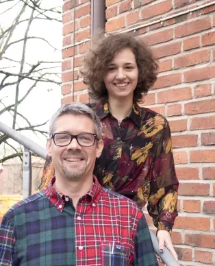 Photo of two people in front of a brick buildning.